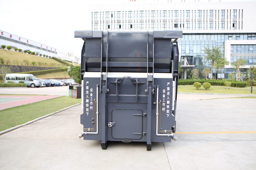 Rear view of a movable refuse compactor at a waste equipment facility