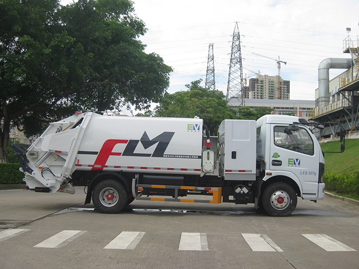 Side view of an electric garbage compactor truck with rear compaction system