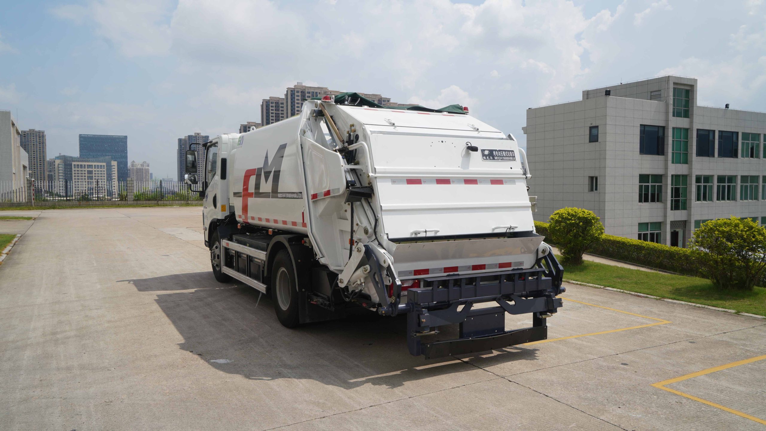 White compactor garbage truck operating in an urban environment