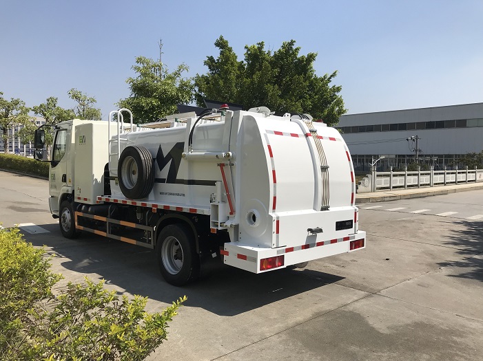 Side view of a sealed wet waste collection truck body in an outdoor sanitation vehicle yard